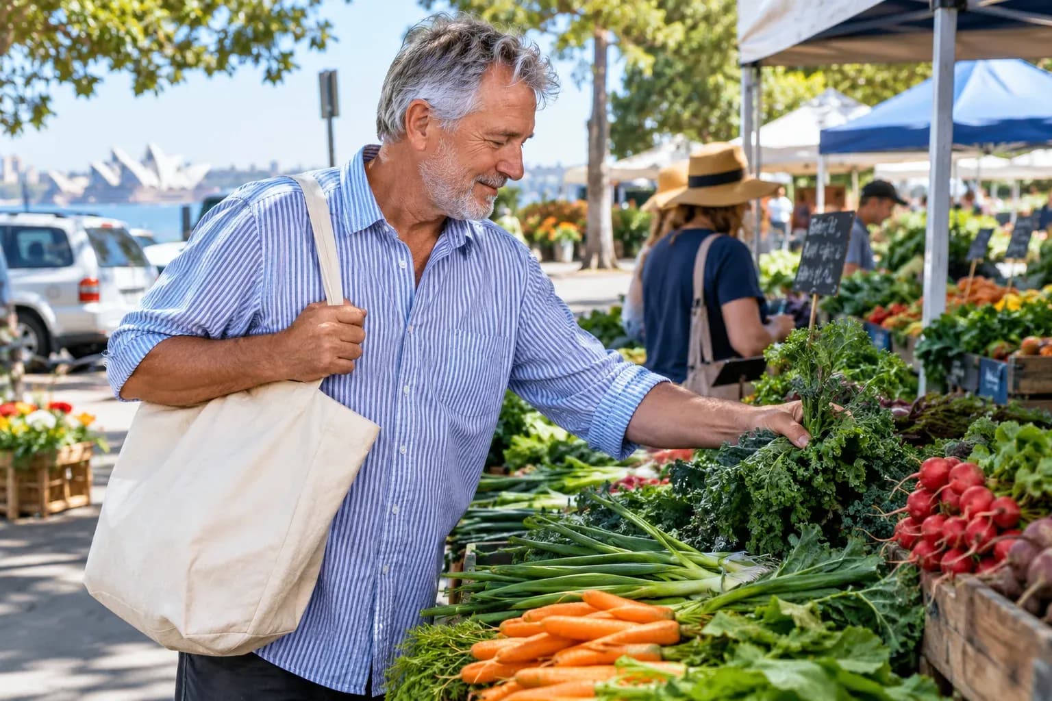 An older man in a striped shirt choosing vegetables with a reusable canvas bag at an outdoor produce stall
