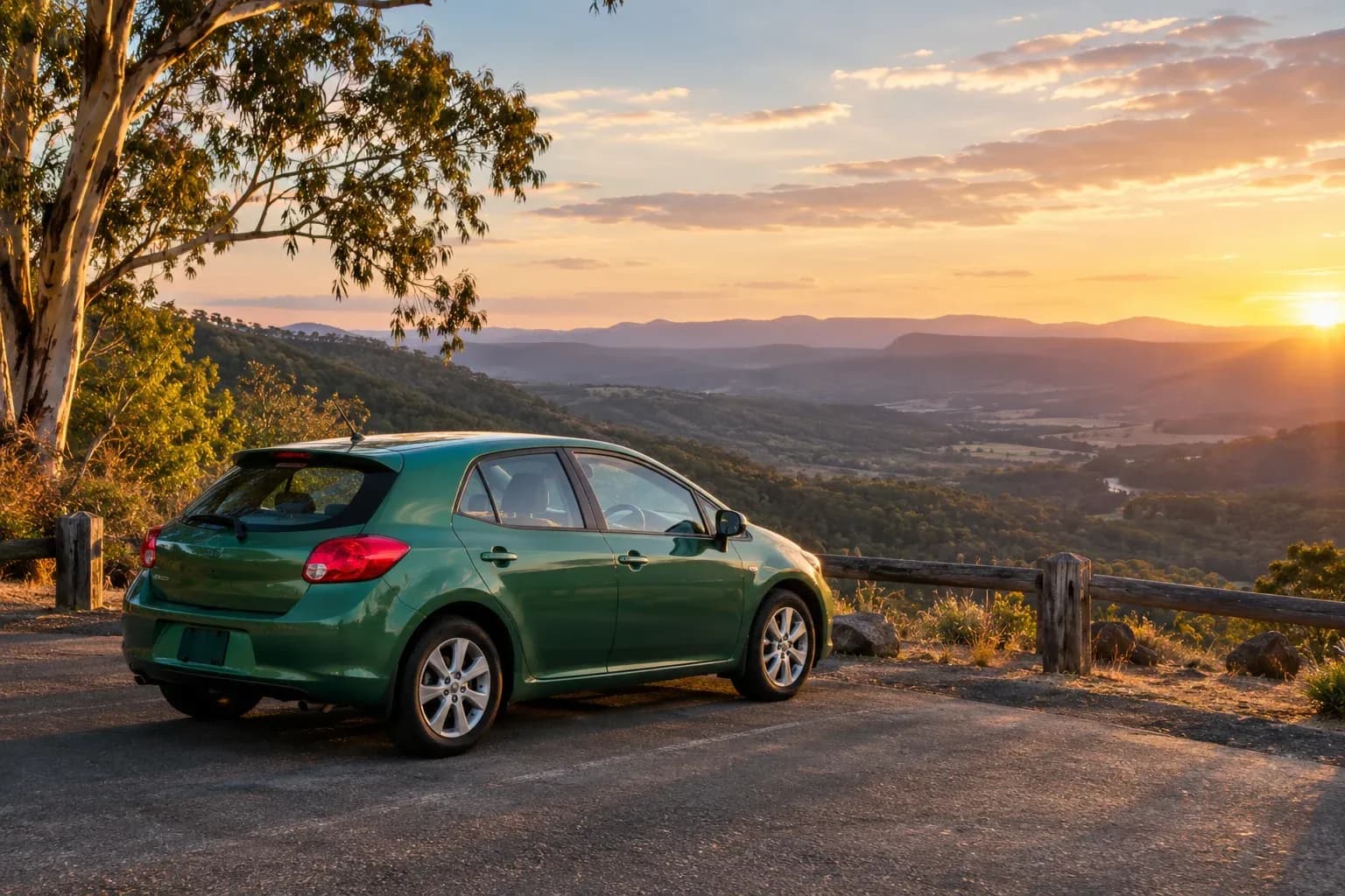 A practical green hatchback parked at a scenic country rest area, eucalyptus valley beyond